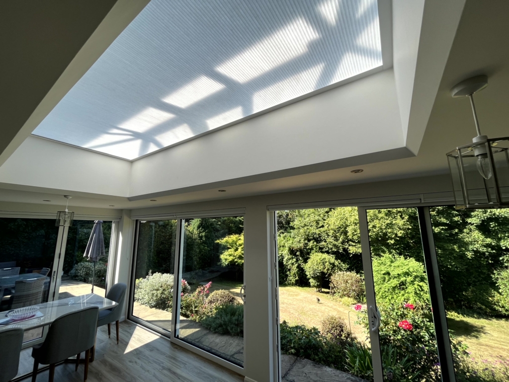White roof lantern blinds in a kitchen with windows facing to the garden