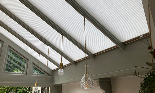 White roof lantern blinds in the kitchen with gable windows facing to the garden